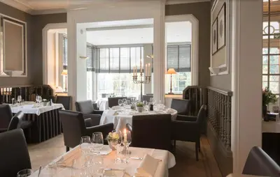 a restaurant with white tables and chairs and windows at Hotel Hippocampus in Mol