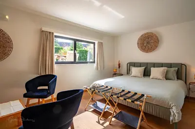 a bedroom with a bed and two chairs and a window at Guest house Huize De Wit in Keerbergen