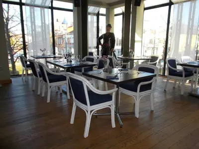 a man standing in a restaurant with tables and chairs at Hotel De Swaen in Herentals