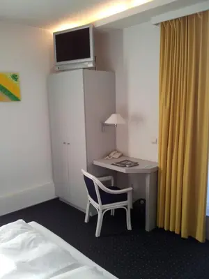 a room with a desk with a chair and a bed at Hotel De Swaen in Herentals