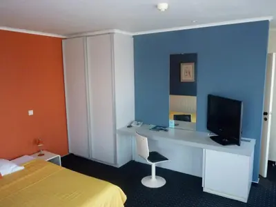 a bedroom with a bed and a desk with a computer at Hotel De Swaen in Herentals