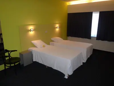 a hotel room with two beds and a chair at Hotel De Swaen in Herentals
