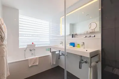 a bathroom with a sink and a tub and a mirror at Thon Hotel EU in Brussels
