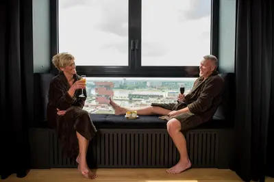 two people sitting on a window sill drinking wine at Exclusieve privé wellness penthouse SkyNooz in Antwerp