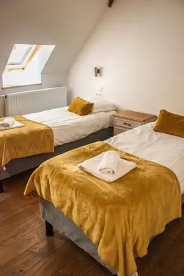 a bedroom with two beds with yellow sheets and a window at B&B La Ferme de l'Hosté in Wavre