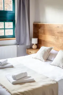a white bed with two towels on top of it at B&B La Ferme de l'Hosté in Wavre