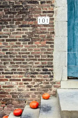 three pumpkins on the sidewalk in front of a brick building at B&B La Ferme de l'Hosté in Wavre
