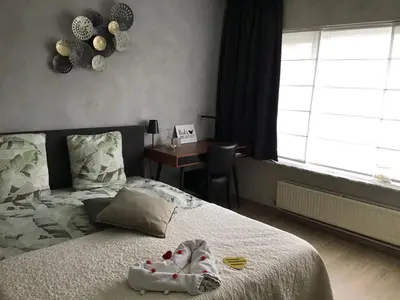 a bedroom with a bed and a desk in a window at Guesthouse De Steenberg tweepersoonskamer met grote badkamer, kitchenette en tuinzicht op de eerste verdieping in Geel