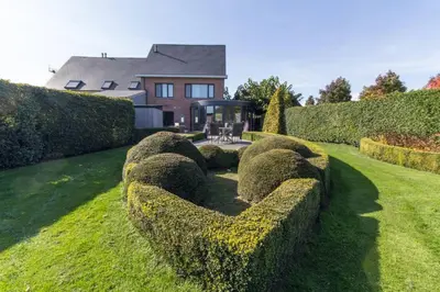 a row of hedges in front of a house at Guesthouse De Steenberg tweepersoonskamer met grote badkamer, kitchenette en tuinzicht op de eerste verdieping in Geel