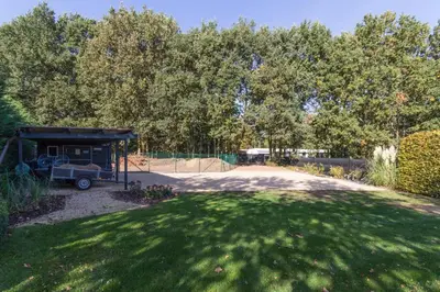 a garden with a car parked under a shed at Guesthouse De Steenberg tweepersoonskamer met grote badkamer, kitchenette en tuinzicht op de eerste verdieping in Geel