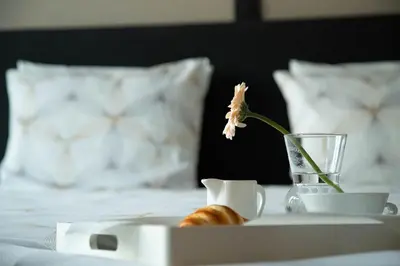a flower in a vase on a tray on a bed at Room 