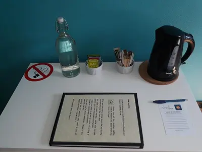 a white counter with a bottle and a table with a book at Room 