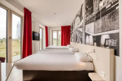 a row of beds in a room with red curtains at B&B HOTEL Antwerpen Zuid in Antwerp