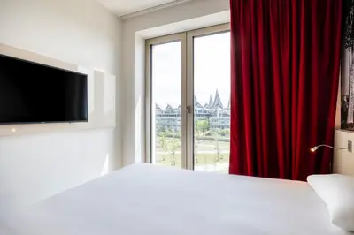 a bedroom with a large window with a red curtain at B&B HOTEL Antwerpen Zuid in Antwerp