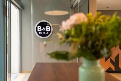 a vase of flowers on a table with a sign at B&B HOTEL Antwerpen Zuid in Antwerp