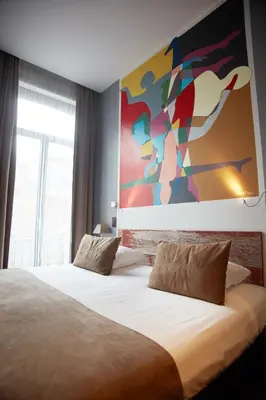 a bedroom with a bed with a large painting on the wall at Boutique Hotel Saint-Géry in Brussels