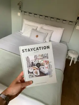a person holding a magazine in front of a bed at B&B PETIT PRINCE, GENT in Ghent