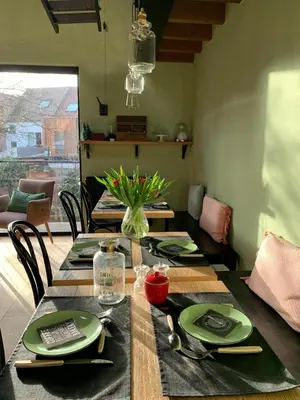 a dining room table with green plates and a vase of flowers at B&B PETIT PRINCE, GENT in Ghent