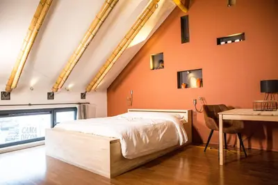a bedroom with an orange wall with a bed and a table at BNB Nest in Ghent