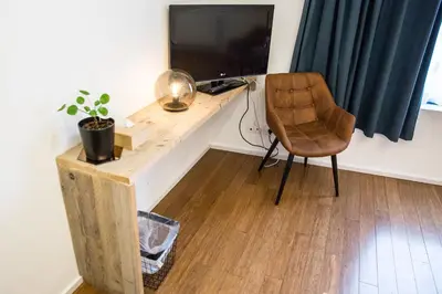 a desk with a chair and a television in a room at BNB Nest in Ghent