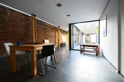 a dining room with a table and a brick wall at BNB Nest in Ghent