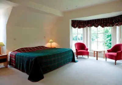 a bedroom with a bed and two red chairs at Bossenstein Golf & Polo Club in Ranst