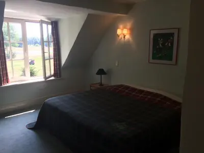 a bedroom with a bed with a plaid blanket and a window at Bossenstein Golf & Polo Club in Ranst