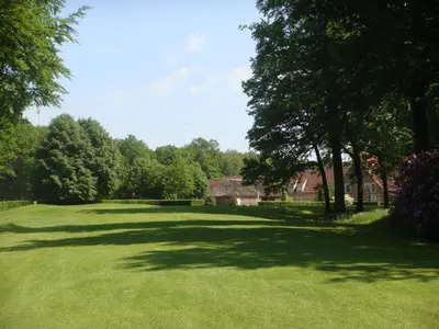 a large green yard with trees and houses at Bossenstein Golf & Polo Club in Ranst