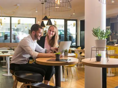 two people sitting at a table with a laptop at Aparthotel Adagio Access Bruxelles Europe Aparthotel in Brussels