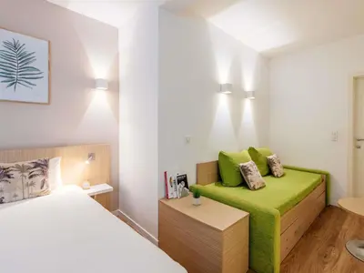 a bedroom with a bed and a green couch at Aparthotel Adagio Access Bruxelles Europe Aparthotel in Brussels