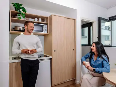 a man and a woman standing in a kitchen at Aparthotel Adagio Access Bruxelles Europe Aparthotel in Brussels