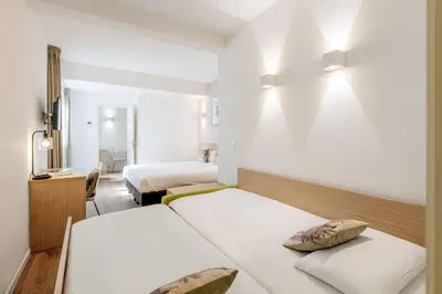 a hotel room with two beds and a mirror at Aparthotel Adagio Access Bruxelles Europe Aparthotel in Brussels