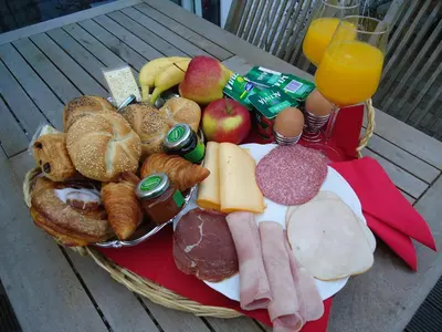 a basket of breakfast foods on a table with a glass of orange juice at B&B Luxe Suites 1-2-3 in Antwerp