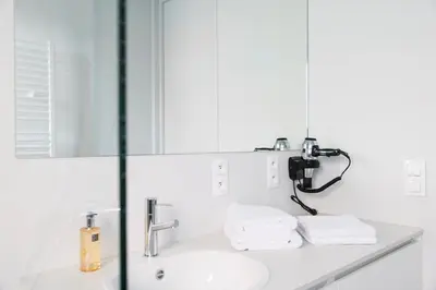 a white bathroom with a sink and a mirror at Skyline Flats Gent in Ghent