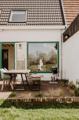 a picnic table and a grill in front of a house at Huisje Nummer Tien in Sint-Laureins