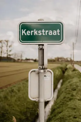 a green street sign that reads kerkrient at Huisje Nummer Tien in Sint-Laureins