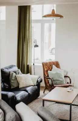 a living room with a couch and a chair at Huisje Nummer Tien in Sint-Laureins