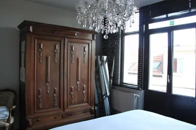 a bedroom with a large wooden cabinet and a chandelier at Puur B&B in Antwerp