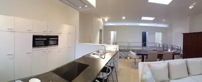 a kitchen with white cabinets and a dining room at Nuvola Loft in Zottegem