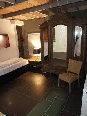 a bedroom with a bed and a chair and a mirror at Nuvola Loft in Zottegem