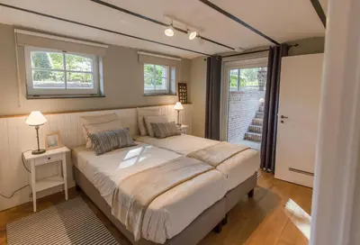 a bedroom with a large bed and two windows at Antonine's Atelier in Hingene