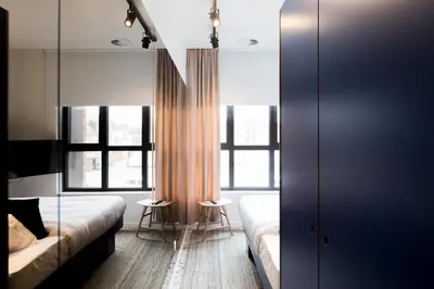 a bedroom with two beds and two windows at YUST Antwerp in Antwerp