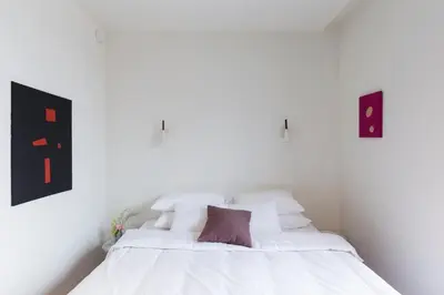 a white bed with white sheets and a purple pillow at YUST Antwerp in Antwerp
