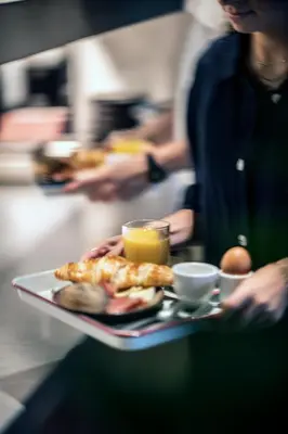 a person holding a tray with a plate of food at YUST Antwerp in Antwerp
