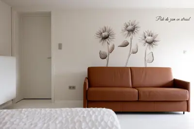 a living room with a couch and flowers on the wall at B&B Ginnekenshoeve in Beerse
