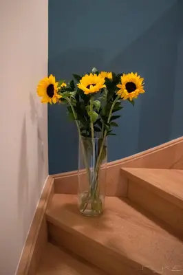 a vase filled with yellow sunflowers sitting on some stairs at De Loteling in Zoersel