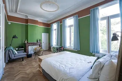a bedroom with a large bed and green walls at 22b&b in Antwerp