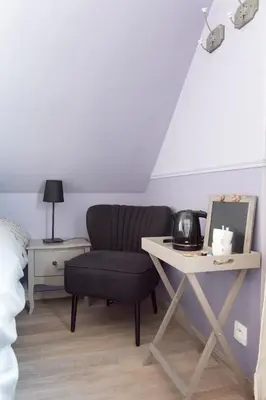 a living room with a table and a chair and a bed at B&B Alegría in Mechelen