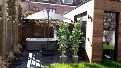 a hot tub with an umbrella and two trees at B&B Alegría in Mechelen