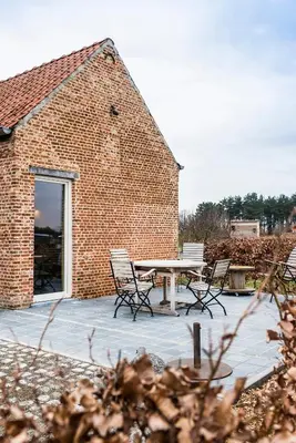 a patio with a table and chairs in front of a brick building at B&B Art.14 in Morkhoven